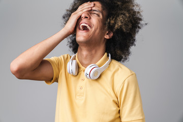 Photo of happy caucasian man with afro hairstyle wearing headphones laughing at camera