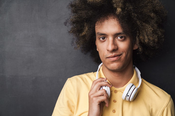 Photo of handsome caucasian man with afro hairstyle wearing headphones looking at camera
