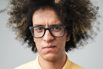 Photo of anxious caucasian man with afro hairstyle wearing eyeglasses frowning at camera with sad...
