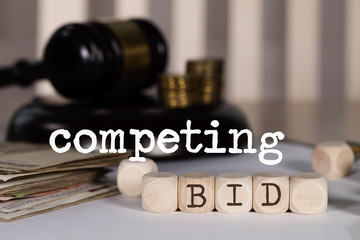 Word COMPETING BID composed of wooden dices.
