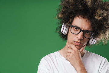Fototapeta na wymiar Photo closeup of brooding young man with afro hairstyle propping up his head and using headphones