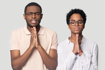Hopeful ethnic man and woman hold hands in prayer - Powered by Adobe