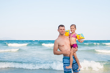 Father holding a baby high with happy face near the sea.