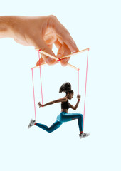 Woman like a puppet in somebodies hands on coral background. Concept of unfair manipulation,...