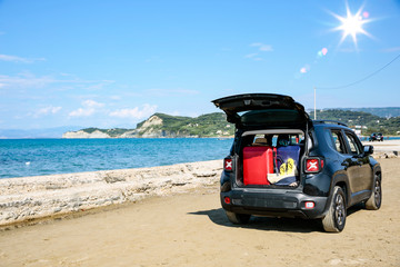 Fototapeta na wymiar Black summer car on the sunny sandy beach. Blue clear sunshine sky view in distance. 