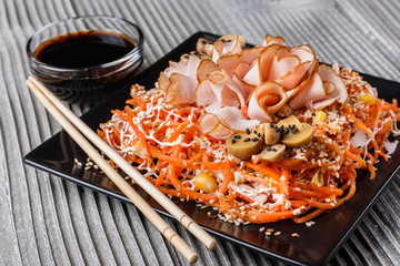 Salad with ham on black square plate
