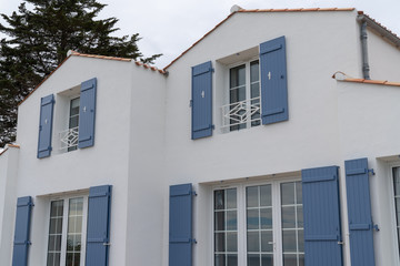 Fototapeta na wymiar Detail of a white house with blue gray shutters and door in Noirmoutier in vendée France