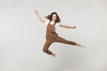 Fototapeta na wymiar Happy active woman jumping in studio isolated on grey background