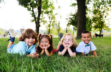 Fototapeta na wymiar four friends of preschool kids playing lying on the grass in the Park on a summer day