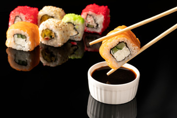 sushi rolls with chopsticks on black background