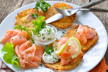 Knusprige Kartoffelpuffer mit Räucherlachs und Creme fraiche mit frischen grünen Kräutern –...