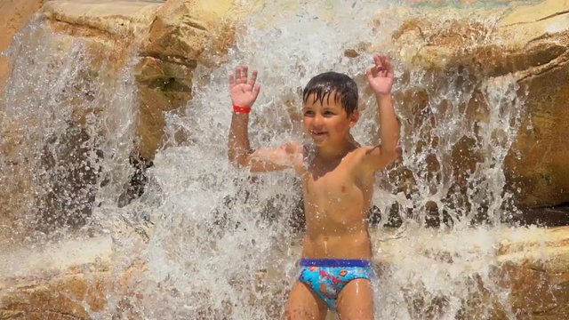 The boy repeats the movement of dance for the coach. Boy is dancing standing on the rocks on the pool