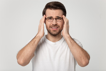Stressed man touching temples suffering from headache studio shot