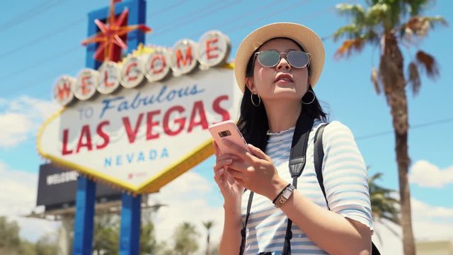 tourist by las vegas sign and surfing on phone