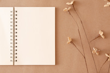 An empty notebook that has been left open and flowers on an old brown background.