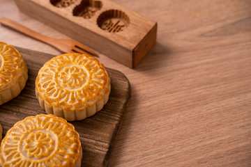 Obraz na płótnie Canvas Round shaped moon cake Mooncake - Chinese style traditional pastry during Mid-Autumn Festival / Moon Festival on wooden background and tray, close up