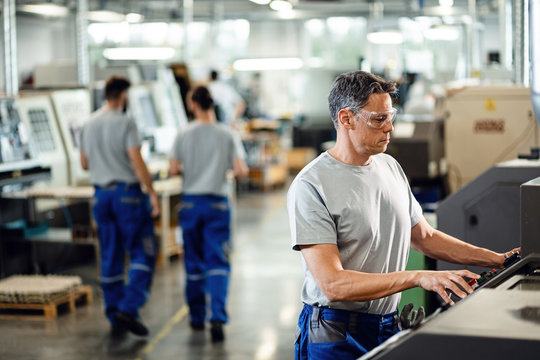 Industrial Facility Employee Working At CNC Machine.