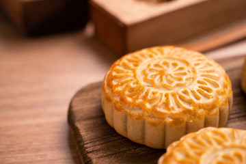 Round shaped moon cake Mooncake - Chinese style traditional pastry during Mid-Autumn Festival / Moon Festival on wooden background and tray, close up