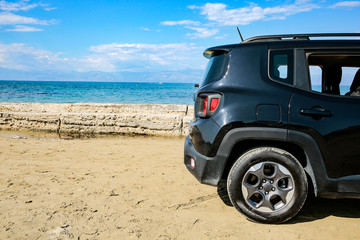 Fototapeta na wymiar Black summer car on the sunny sandy beach. Blue clear sunshine sky view in distance. 