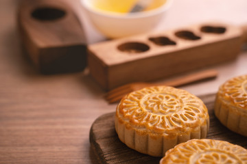 Round shaped moon cake Mooncake - Chinese style traditional pastry during Mid-Autumn Festival / Moon Festival on wooden background and tray, close up