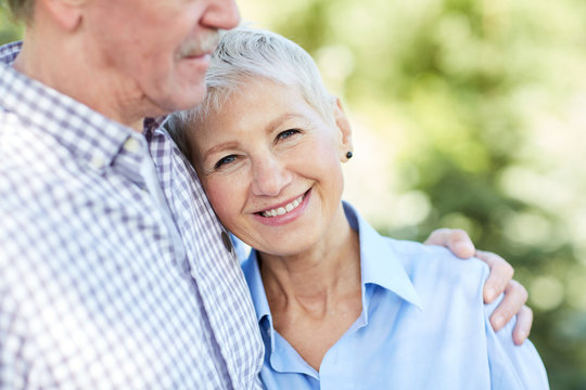 Mid-section portrait of loving senior couple embracing, focus on elegant woman smiling at camera, copy space