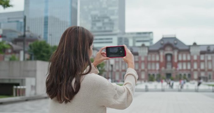 Woman use of mobile phone to take photo in Tokyo station