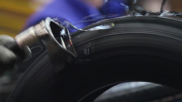 Tool for stripping tires after molding. Tire handling at the factory from excess rubber. Car tiyes production. Detailed production process of car tires, closeup. Rotation of the wheel close up.