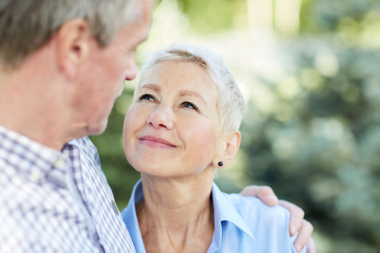 Portrait of loving senior couple embracing and looking at each other focus on elegant woman smiling at husband, copy space