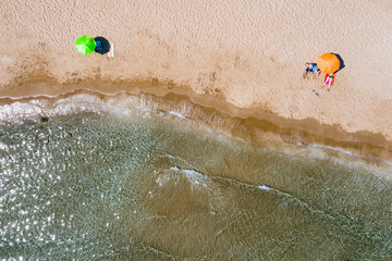 Aerial view of sandy coast with sandy beach and umbrellas and sunbeds. 