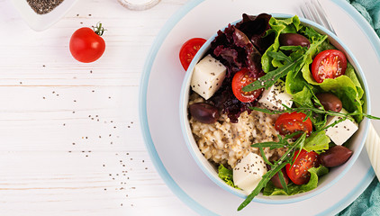 Vegan salad. Breakfast bowl with oatmeal, tomatoes, cheese, lettuce,  and olives. Healthy food. Vegetarian buddha bowl. Top view