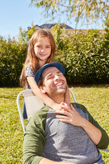Tochter umarmt Vater auf einem Stuhl im Garten