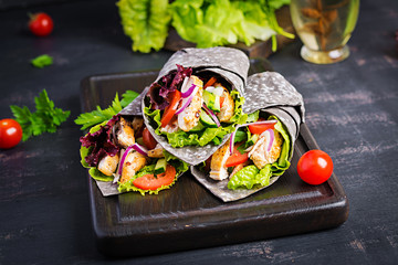 Tortilla with added ink cuttlefish wraps with chicken and vegetables on black background. Chicken...