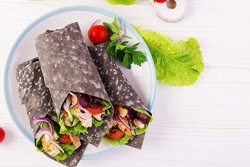 Tortilla with added ink cuttlefish wraps with chicken and vegetables on white background. Chicken burrito, mexican food. Top view
