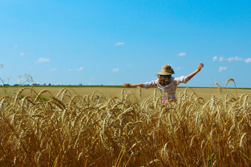 Happy young girl walking on a wheat meadow. People, nature, travel concept.