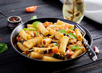 Rigatoni pasta with chicken meat, eggplant in tomato sauce in bowl. Italian cuisine.