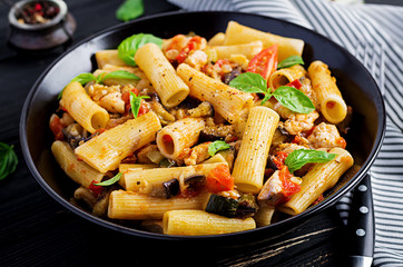 Rigatoni pasta with chicken meat, eggplant in tomato sauce in bowl. Italian cuisine.