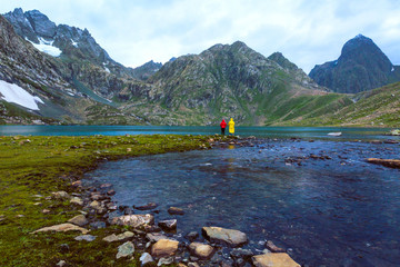 Friends fishing at Vishnusar lake on Kashmir great lakes trek in Sonamarg, India. Rocky terrain and  turquoise lake/tarn with snow mountains and glacier. Amazing nature. Hiking Trekking in Himalayas