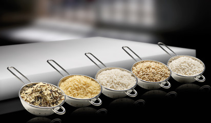 Coladores con tipos de arroz sobre fondo negro. Colanders with types of rice on a black background.
