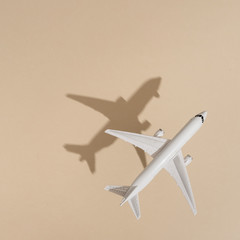Top view of airplane on sand color background. Flat lay. Minimal summer travel concept. Creative...
