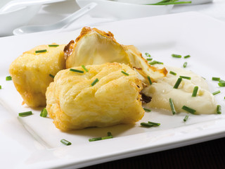 Merluza frita con cebollino, sobre fondo blanco, vista cenital. Fried hake with chives, on white background, overhead view.