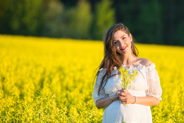 Naklejka na ściany i meble pregnant girl in a white dress. Outdoor natural portrait of beautiful pregnant woman in white dress