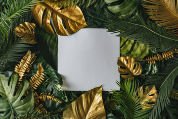 Creative nature background. Gold and green tropical palm leaves. Minimal summer abstract jungle or forest pattern. White paper frame copy space.