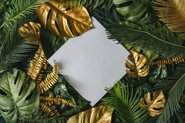 Creative nature background. Gold and green tropical palm leaves. Minimal summer abstract jungle or forest pattern. White paper frame copy space.