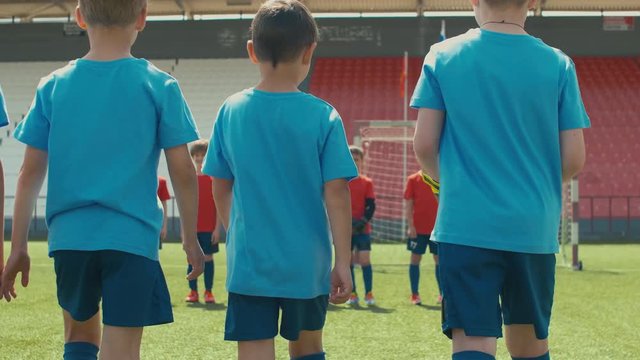 One team of young soccer players coming closer to another before match and skipper putting his leg on ball