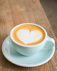 Cappuccino mit Latte Art Herz auf einem Holztisch