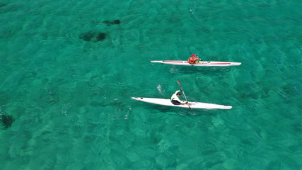 Aerial drone photo of fit men practising sport canoe in tropical open ocean bay with turquoise clear sea