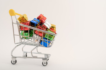 Christmas gifts in a supermarket trolley on white background. Online shopping concept - trolley full of gifts. Black Friday and Cyber Monday