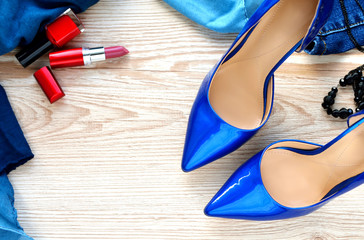 Beautiful female high-heeled shoes, accessories and cosmetics on a wooden background.