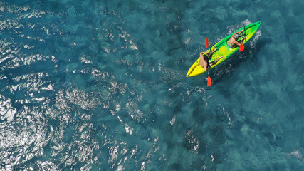 Aerial drone photo of fit couple practising on a colourful canoe in turquoise open ocean bay with crystal clear sea