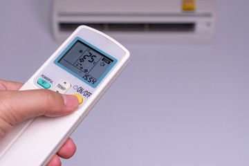 Man hand switching on air conditioner 25 celsius. Energy saving concept.